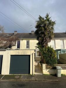 a white house with a garage and a palm tree at Maison de ville proche de tout, 5min du centre ville & 20min de la plage in Quimper
