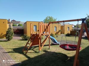 a playground with a slide and a swing set at Domki PrzystańTu in Jastarnia +18 photos