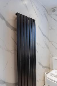 a black radiator in a bathroom with a toilet at The Gatehouse in Paisley