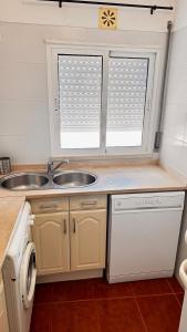 a kitchen with a sink and two windows at Cabana Fersan in Cabanas de Tavira