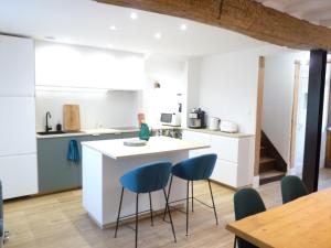 a kitchen with a white island and blue chairs at Le Passage du Roi, maison de ville, jardin et garage au coeur d'Amboise in Amboise