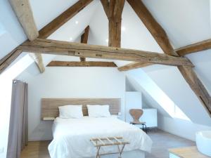 an attic bedroom with a white bed and wooden beams at Le Passage du Roi, maison de ville, jardin et garage au coeur d'Amboise in Amboise