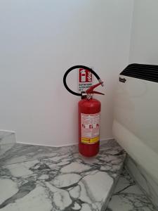 a red fire extinguisher sitting next to a toilet at La Villetta di Sabrina in Marsala