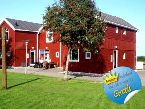 eine rote Scheune mit einem Schild im Gras in der Unterkunft Feriecenter & Vandland Øster Hurup in Øster Hurup