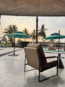 a chair and a table with umbrellas next to a pool at MERAKI BEACH RESORT Lodges in Lomé