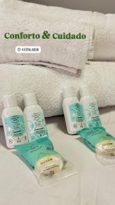 a group of four bottles of lotion next to towels at A Estalagem Pousada in Monteiro Lobato