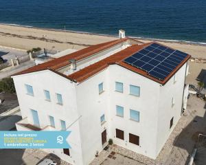 a white building with solar panels on the roof at RS322 - Marcelli, bilocale fronte mare con spiaggia inclusa in Marcelli