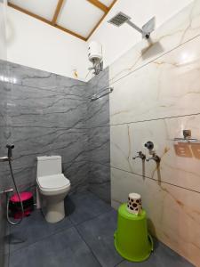 a bathroom with a toilet and a green stool at Casino Beach Homestay in Alleppey +34 photos