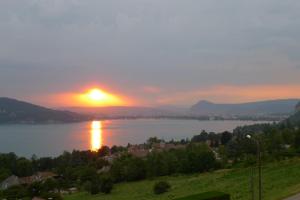 a sunset over a lake with the sun setting at Le Clos Du Lac - location de chambres in Veyrier-du-Lac