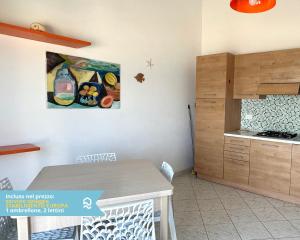 a kitchen with a table and a painting on the wall at RS323 - Marcelli, bilocale fronte mare con spiaggia inclusa in Marcelli