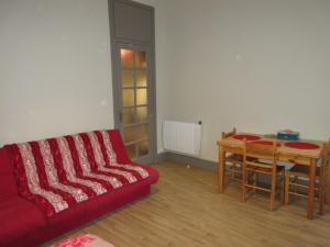 sala de estar con sofá rojo y mesa en Résidence Angleterre, en Cauterets