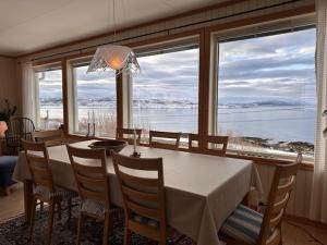 a dining room with a table and chairs and a large window at Lenangsvegen 2929 in Russelv