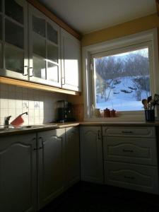 a kitchen with white cabinets and a large window at Lenangsvegen 2929 in Russelv