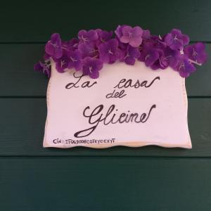 a sign with purple flowers on a wall at la Casa del Glicine in Mortaiolo