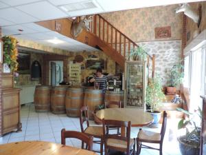 a woman in a kitchen with barrels in a restaurant at Auberge de la Normandie in Junhac
