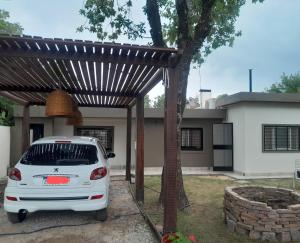 ein weißes Auto, das unter einer Pergola vor einem Haus parkt in der Unterkunft CASA DE CAMPO cerca de rosario in Pueblo Esther