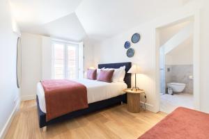 a white bedroom with a bed and a bathroom at Ando Living - Santa Justa 79 House in Lisbon