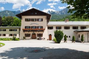 a large white building with mountains in the background at BSW Hotel Hubertus-Park in Schönau am Königssee