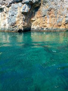 a body of water next to a rocky cliff at Casa Vacanza Il Pontile Mini Appartamento in Cipollina