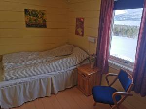 une chambre avec un lit, une chaise et une fenêtre dans l'établissement Feriehus ved Fjellfroskvatnet, à Skjold