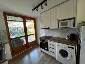 a kitchen with a washing machine and a microwave at Diána Apartman in Alsóörs
