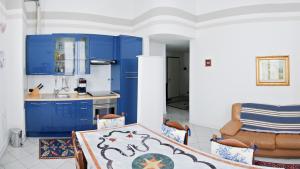 サンタ・マルゲリータ・リグレにあるRomeo Apartmentsのキッチン(青いキャビネット、テーブル、ソファ付)