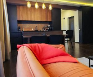 un salon avec un canapé orange et une cuisine dans l'établissement Lavish Apartment, à Dej