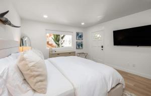 a white bedroom with a large bed and a flat screen tv at The South Bay Retreat in Redondo Beach +34 photos