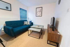 a living room with a blue couch and a table at Stunning New Town Centre flat in Wigan in Wigan