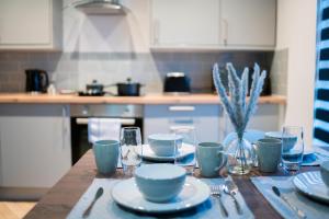a table with plates and glasses on a kitchen at Stunning New Town Centre flat in Wigan in Wigan +5 photos