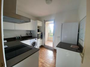 une cuisine avec des armoires blanches et un réfrigérateur dans l'établissement Charmant 2 pièces parc piscine, à Vence