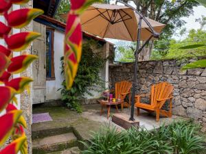 a patio with two chairs and an umbrella at Jardim da Música Tiradentes in Tiradentes