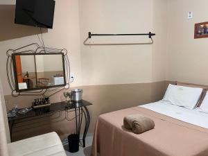 a small room with a bed and a mirror at Hotel Bee's Sorriso in Sorriso