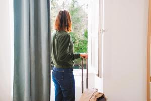a woman is looking out of a window with a suitcase at Confortable T2 sur les rives de la Charente in Angoulême +45 photos