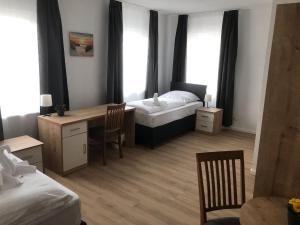 1 Schlafzimmer mit 2 Betten, einem Schreibtisch und Stühlen in der Unterkunft Hotel am Wasserturm in Crailsheim + 37 Fotos