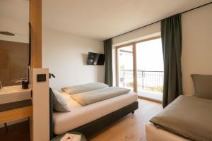 a bedroom with two beds and a bathroom with a window at San Antonia in Caldaro