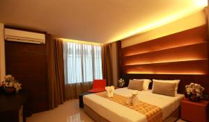 Schlafzimmer mit einem Bett mit einem roten Stuhl und einem Fenster in der Unterkunft The Bangkok Major Suite in Bangkok