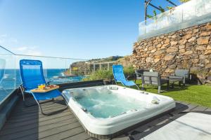 a hot tub on a deck with chairs and the ocean at Aqui ha Casa by AH in Gaula