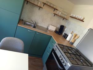 a small kitchen with a stove and a sink at Mobil-home rénové tout confort, terrasse couverte, climatisation, arrivée autonome in Fourmies