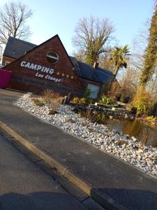 a building with a sign on it next to a river at Mobil-home rénové tout confort, terrasse couverte, climatisation, arrivée autonome in Fourmies +5 photos