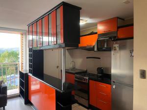 a small kitchen with orange and black cabinets at Departamento acogedor y céntrico in Temuco