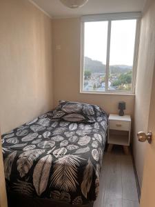a small bedroom with a bed and a window at Departamento acogedor y céntrico in Temuco +5 photos
