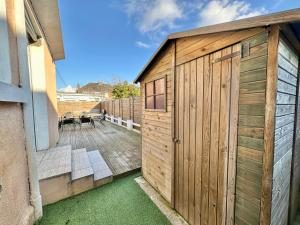 a wooden shed with a wooden door on a patio at Petite maison de vacances - Terrasse - Berck-Plage in Berck-sur-Mer