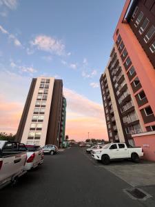 a parking lot with cars parked in front of two tall buildings at Departamento acogedor y céntrico in Temuco