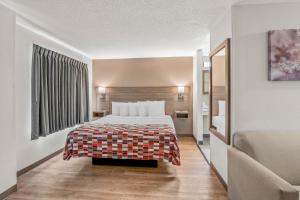 a hotel room with a bed and a couch at Red Roof Inn Southfield in Southfield