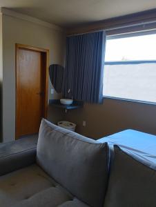 1 dormitorio con sofá, ventana y puerta en Caraguá House, en Caraguatatuba