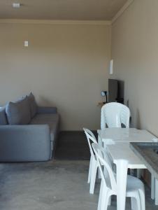una sala de estar con sofá y mesas y sillas blancas. en Caraguá House, en Caraguatatuba