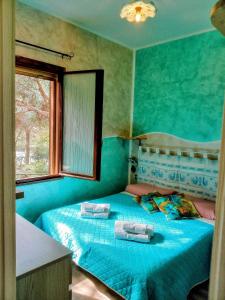 ein blaues Schlafzimmer mit einem Bett mit Handtüchern darauf in der Unterkunft Pinus Village, Pula, sud Sardegna casa vacanze Vera's House in Fort Village