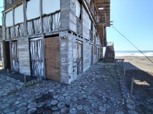 an old building on the beach next to the ocean at Las delicias del paraiso in Armería