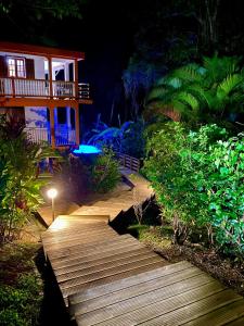 a wooden pathway leading to a house at night at Ti Lodge Nature - milieu de villa - piscine partagée - location vacances Guadeloupe in Sainte-Anne